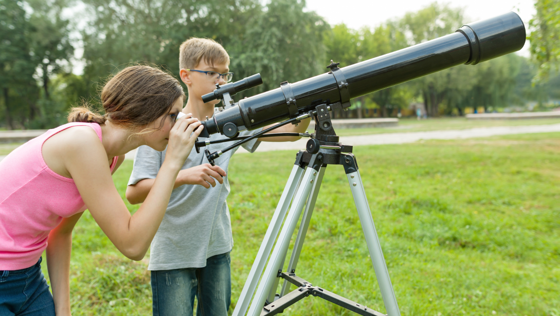 Two kids playing with a telescope
